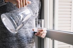 crop-man-pouring-water-near-window