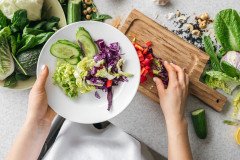 plate-with-chopped-fresh-vegetables-female-hands-kitchen-top-view